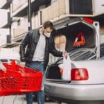 Ojciec z synem pakują zakupy do bagażnika auta na parkingu