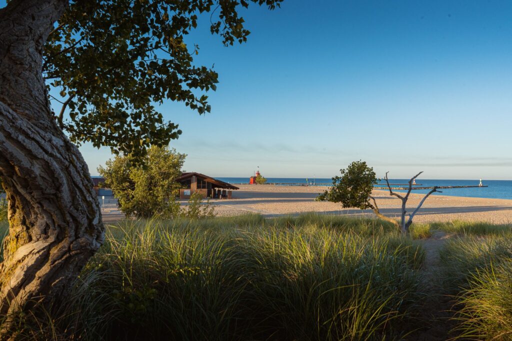 Czerwona latarnia morska przy piaszczystej plaży i zieleni